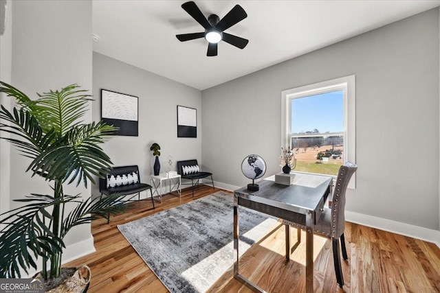 office space featuring a ceiling fan, baseboards, and wood finished floors