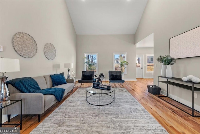 living room featuring high vaulted ceiling, wood finished floors, and baseboards