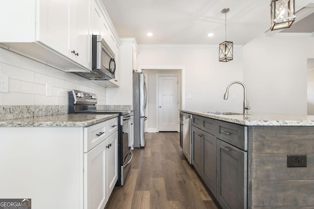 kitchen with a kitchen island with sink, stainless steel appliances, a sink, white cabinets, and backsplash