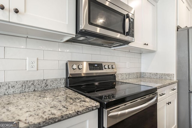 kitchen featuring light stone counters, appliances with stainless steel finishes, white cabinets, and backsplash