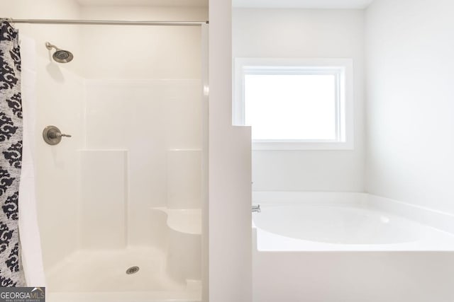 bathroom featuring a shower stall and a bath