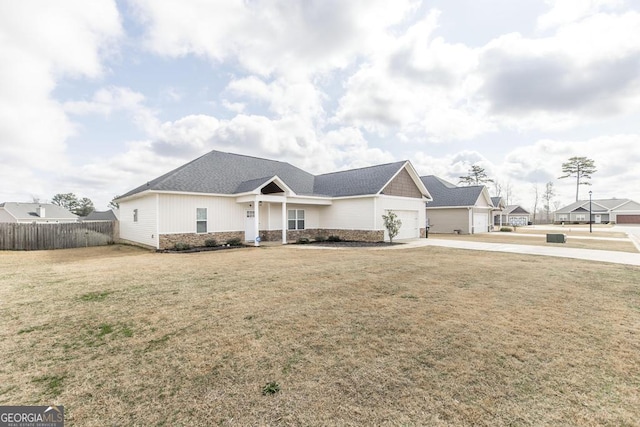 view of front facade with an attached garage, fence, concrete driveway, stone siding, and a front lawn