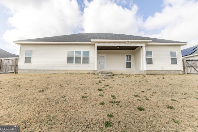 rear view of house featuring roof with shingles and fence