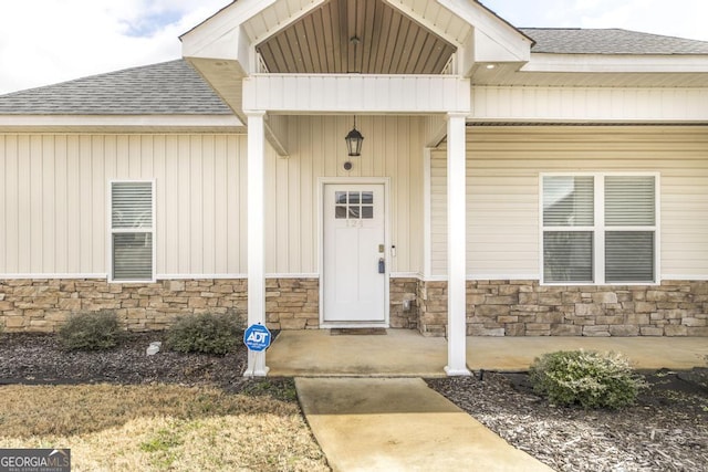 property entrance with stone siding and a shingled roof