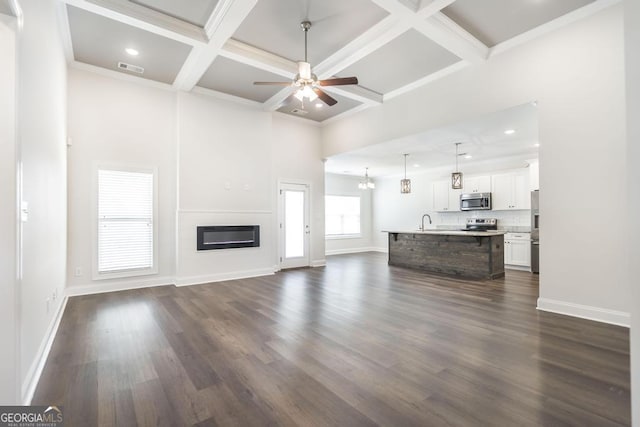 unfurnished living room featuring a glass covered fireplace, dark wood finished floors, baseboards, and ceiling fan with notable chandelier