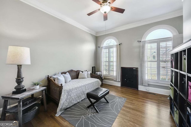 bedroom featuring ornamental molding, a ceiling fan, baseboards, and wood finished floors