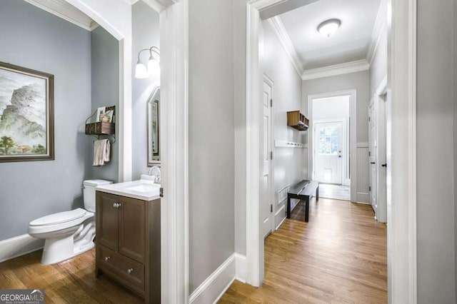 hallway featuring a sink, baseboards, ornamental molding, and wood finished floors