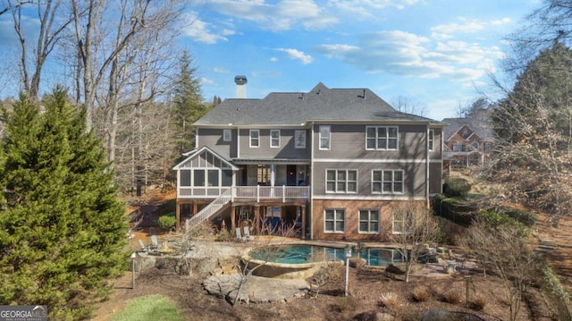 rear view of house featuring stairs, a patio area, a sunroom, and an outdoor pool