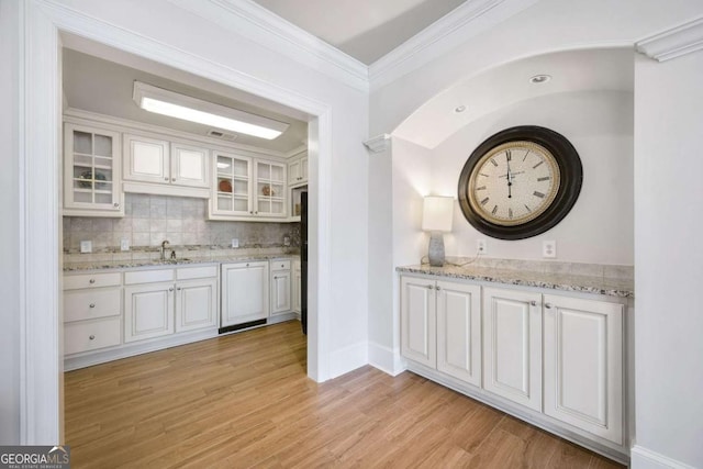 kitchen featuring ornamental molding, decorative backsplash, light wood-style flooring, and white cabinets