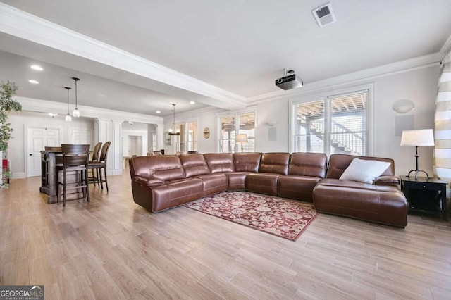 living area with ornamental molding, visible vents, ornate columns, and wood finished floors