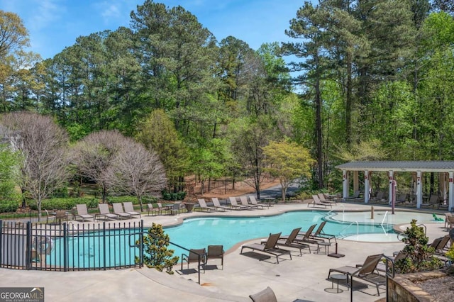 community pool with a patio area and fence