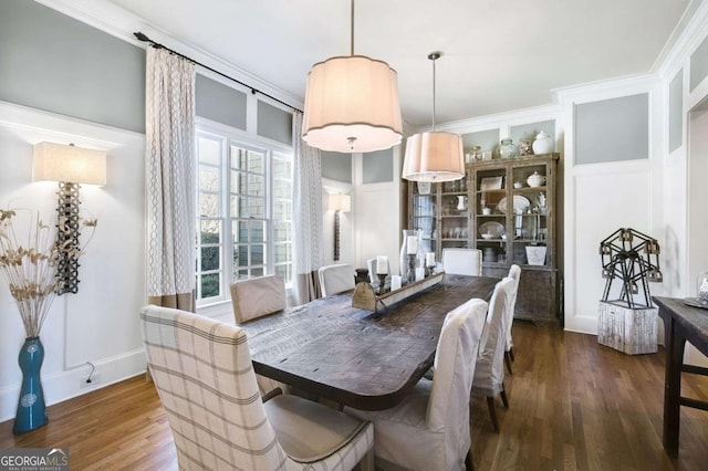 dining room with ornamental molding, a decorative wall, and wood finished floors