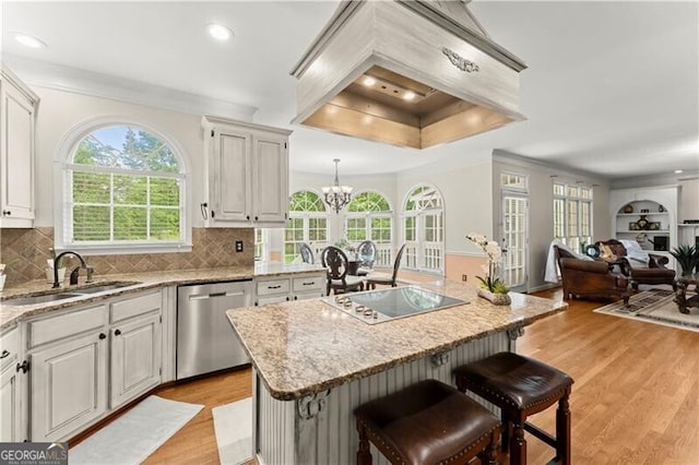 kitchen with light wood-style flooring, electric stovetop, premium range hood, a sink, and stainless steel dishwasher
