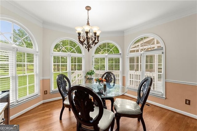 dining space featuring ornamental molding, light wood-style flooring, and an inviting chandelier