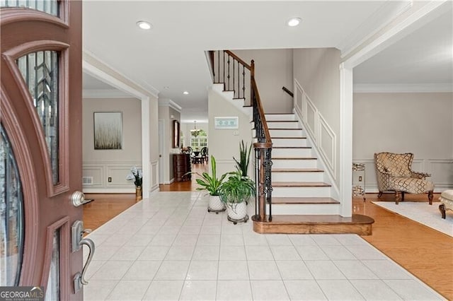 entrance foyer featuring stairway, a decorative wall, crown molding, and recessed lighting