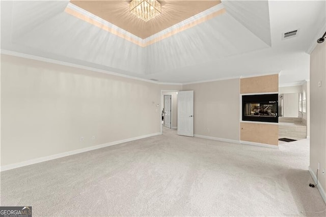 unfurnished living room with carpet, ornamental molding, a raised ceiling, and baseboards
