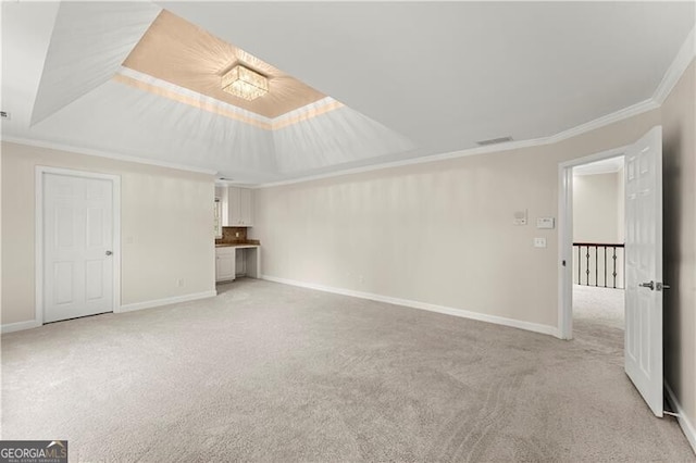 unfurnished living room featuring baseboards, a tray ceiling, light colored carpet, and ornamental molding