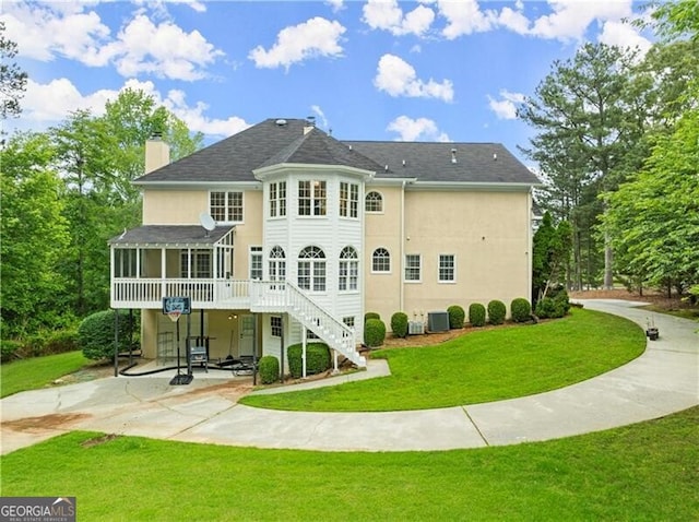 back of property with a sunroom, a chimney, stairs, a yard, and a patio area