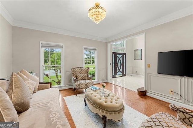 living room featuring a wainscoted wall, ornamental molding, wood finished floors, and a decorative wall