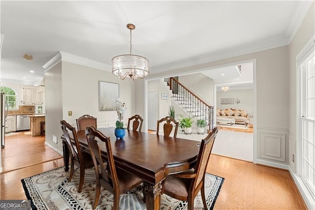 dining room featuring light wood-style floors, stairs, ornamental molding, and a notable chandelier