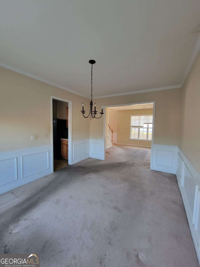 unfurnished dining area featuring a chandelier, carpet floors, wainscoting, and a decorative wall