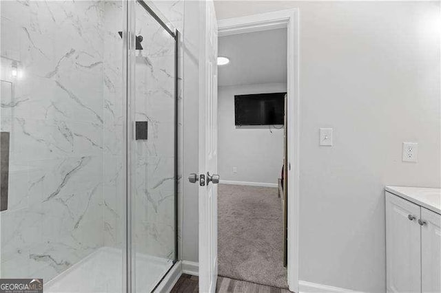 full bath with a marble finish shower, baseboards, and vanity