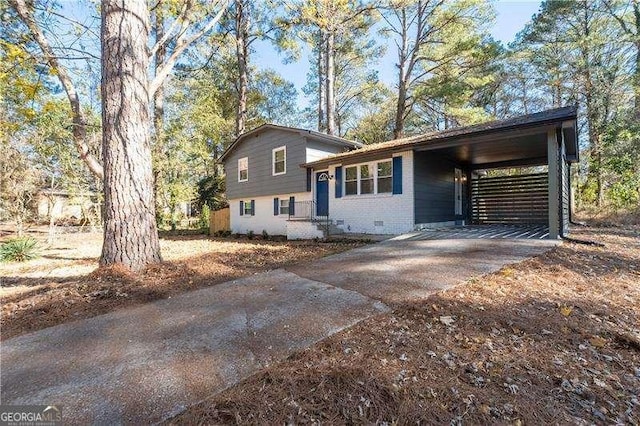 split level home featuring a carport, concrete driveway, and brick siding