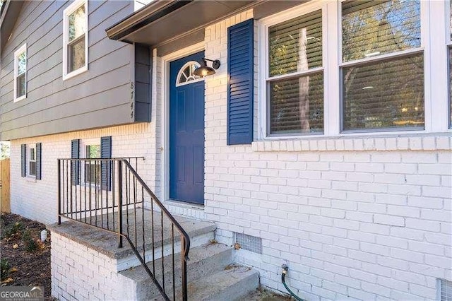 entrance to property featuring crawl space and brick siding