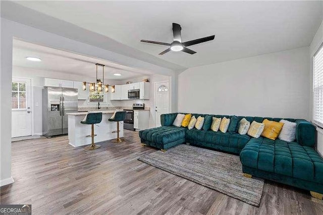 living room with ceiling fan with notable chandelier and wood finished floors