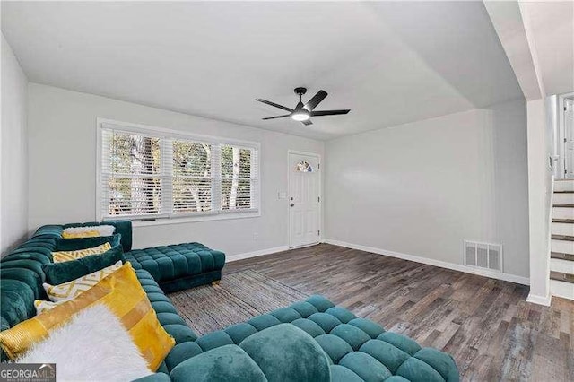 living area featuring a ceiling fan, visible vents, baseboards, and wood finished floors