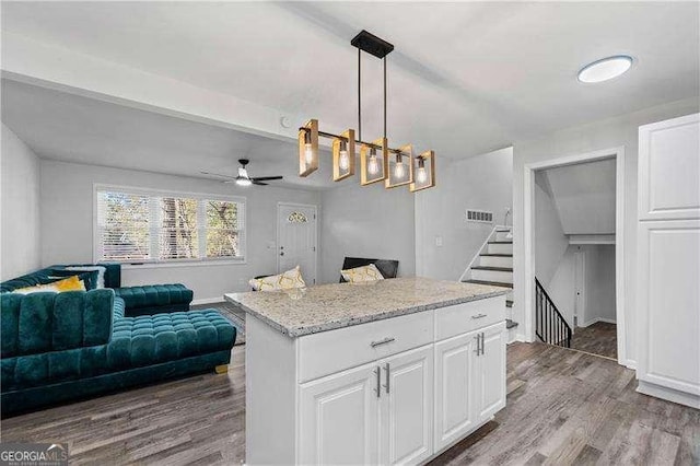 kitchen featuring open floor plan, white cabinets, hanging light fixtures, and wood finished floors