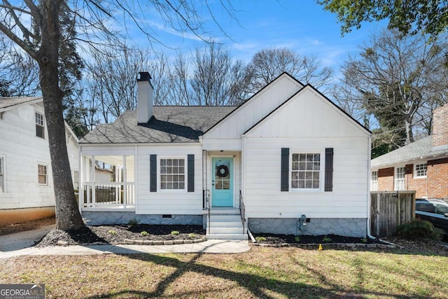 bungalow-style house featuring entry steps, a shingled roof, crawl space, a front lawn, and a chimney