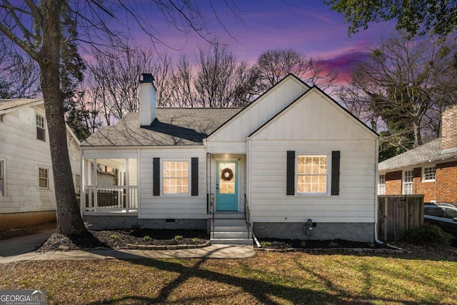 view of front facade with a front yard, crawl space, roof with shingles, and a chimney