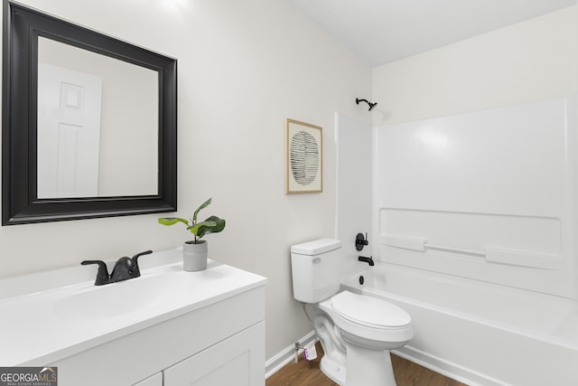 bathroom with baseboards, toilet, wood finished floors, vanity, and shower / washtub combination