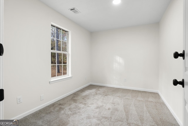 carpeted spare room featuring visible vents and baseboards