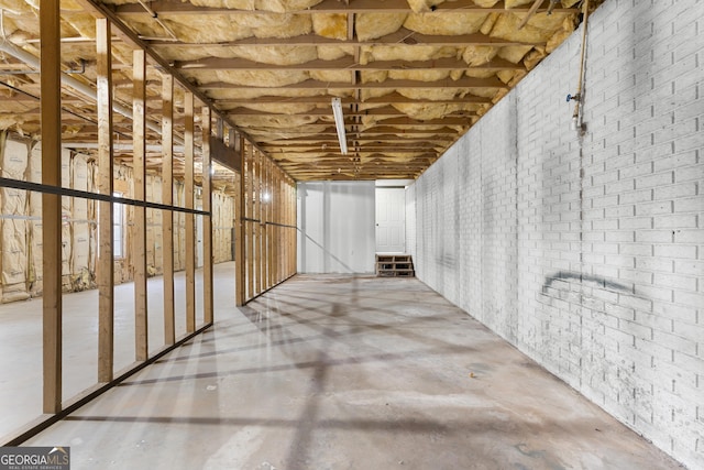 miscellaneous room featuring brick wall and unfinished concrete floors