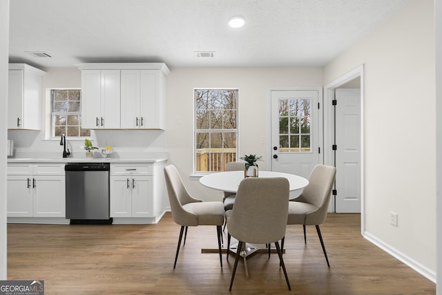 dining area with light wood-type flooring, visible vents, and baseboards