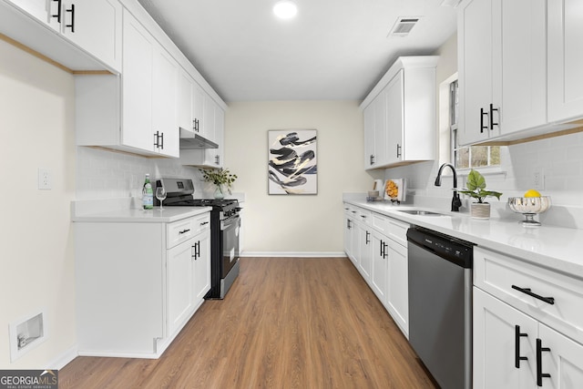 kitchen featuring visible vents, gas range, stainless steel dishwasher, under cabinet range hood, and a sink