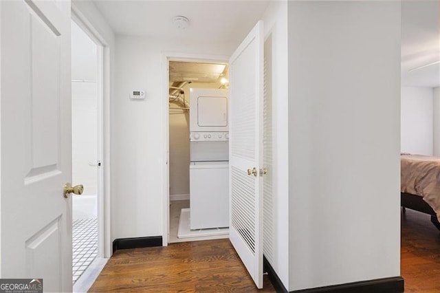 hall with stacked washer and dryer and wood finished floors
