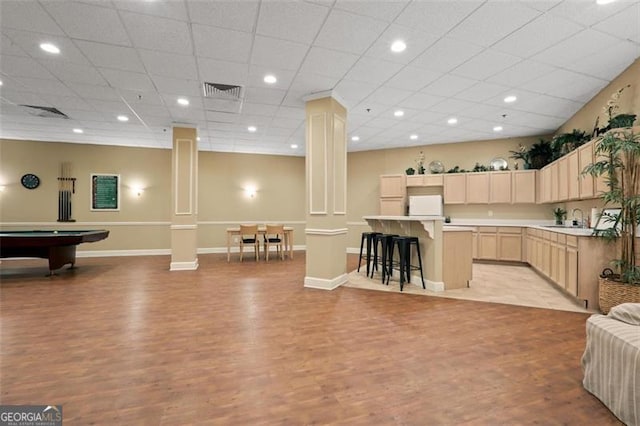 kitchen featuring light brown cabinets, a sink, open floor plan, fridge, and decorative columns