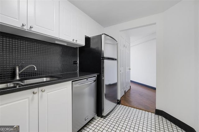 kitchen with dark countertops, appliances with stainless steel finishes, white cabinets, and a sink
