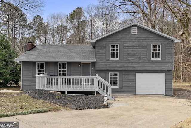 tri-level home with a garage, driveway, a chimney, and a shingled roof