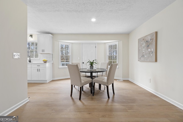 dining space with light wood finished floors, baseboards, a textured ceiling, and recessed lighting