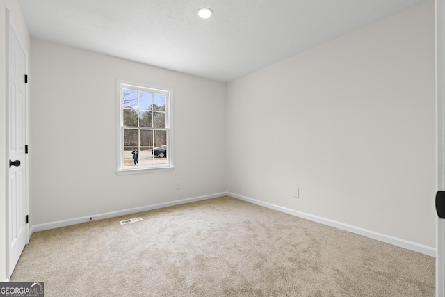 carpeted empty room featuring baseboards, visible vents, and a textured ceiling