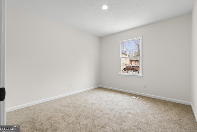 carpeted spare room with visible vents, baseboards, a textured ceiling, and recessed lighting