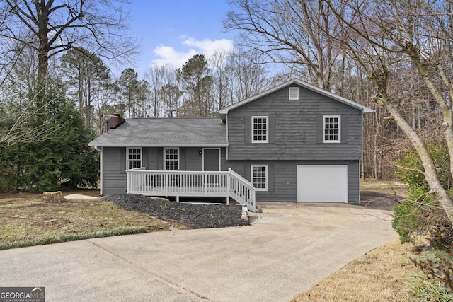 tri-level home featuring a garage, driveway, a chimney, and a deck