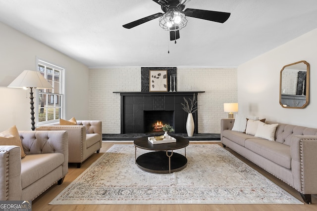 living room with a brick fireplace, brick wall, and wood finished floors