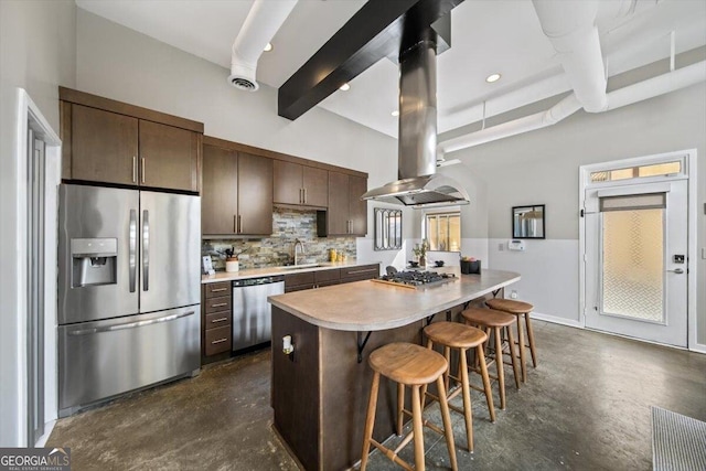 kitchen featuring stainless steel appliances, light countertops, a sink, island range hood, and beamed ceiling