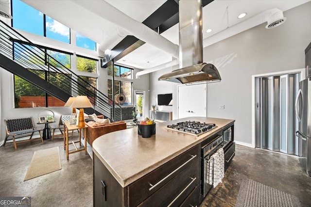 kitchen featuring island range hood, appliances with stainless steel finishes, a center island, a high ceiling, and concrete flooring