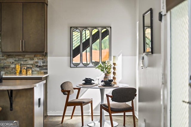 interior space with dark brown cabinetry, tasteful backsplash, baseboards, and light countertops